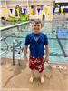 A boy standing in front of a swimming pool. 