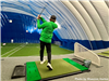 A boy teeing off at an indoor golfing facility. 