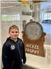 A boy standing in front of the Nickel Trophy. 