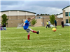 A boy kicking a soccer ball at a goal. 