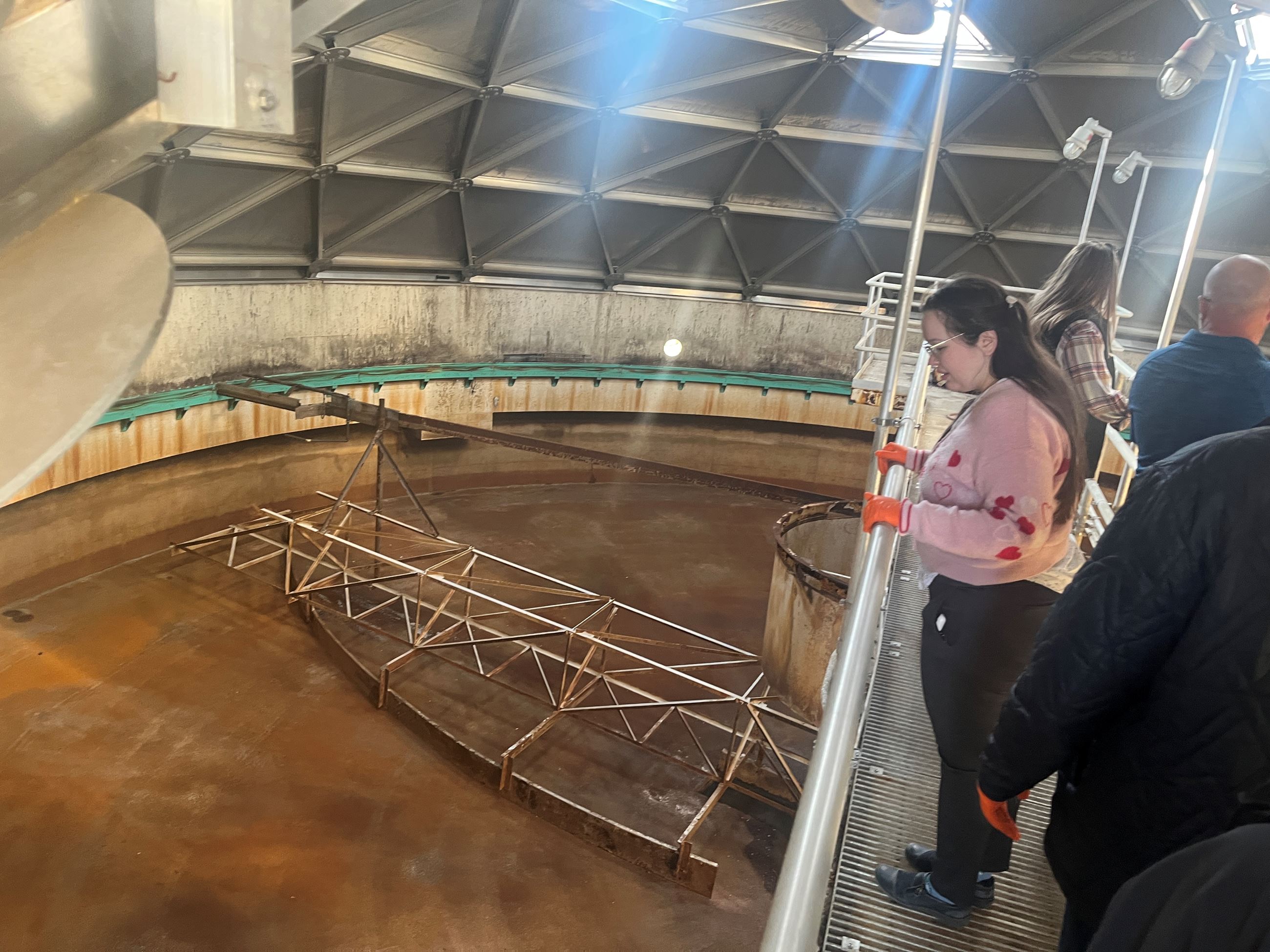 Citizen Academy attendees tour walk along a catwalk in a structure at the Wastewater Treatment Plant