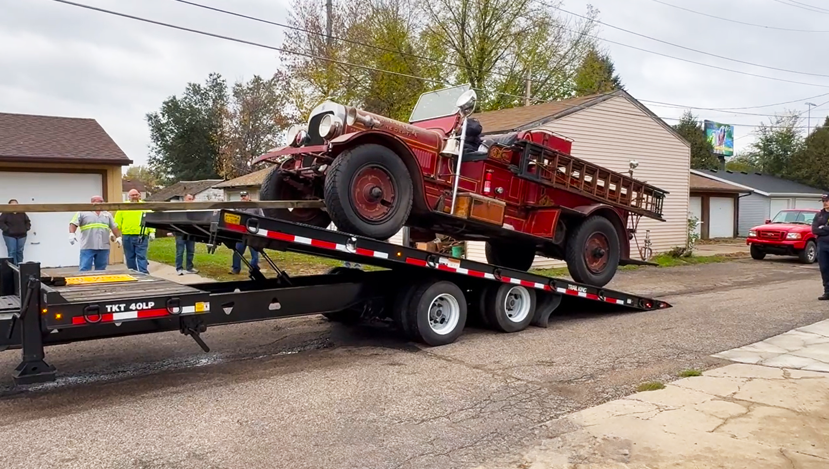 A firetruck is pulled onto a trailer to be transported from an alley. 